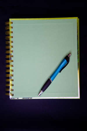 green notebook and pen on black background