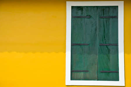 green window on yellow wallの写真素材