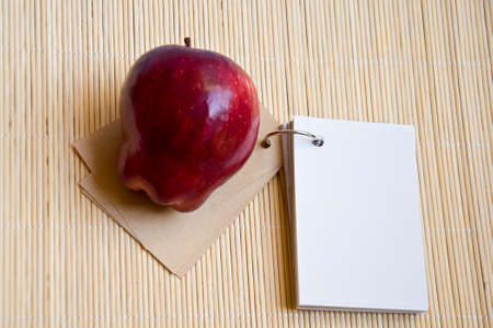 white paper and red apple on bamboo matの写真素材