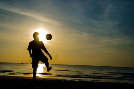 silhouette of man playing soccer on the beachの写真素材