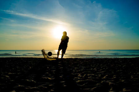 silhouette of man playing soccer on the beachの写真素材