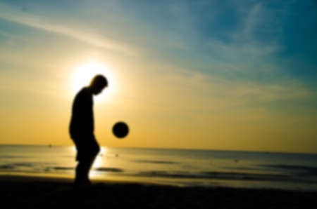 silhouette of man play soccer on the beach with blur styleの写真素材