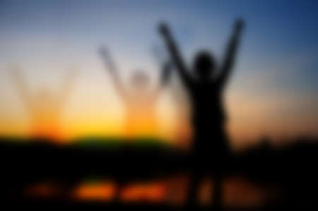 silhouette of girl victory and sundown at the lake with blurの写真素材