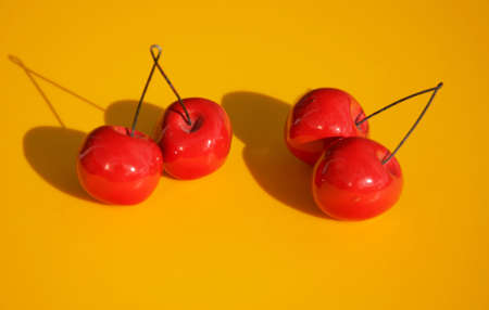 Red cherries isolated on yellow backgroundの写真素材