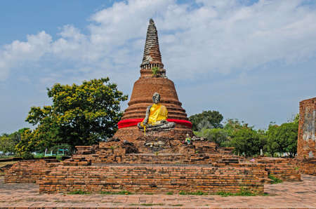 Buddha statue with Yellow robe in the old sanctuary with pagoda background, Thailandの写真素材