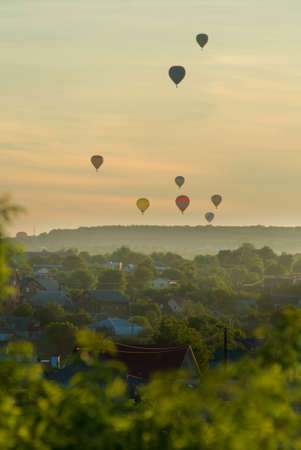 Striped hot air balloon flying over earth, evening landscape and the city with little houses, a river in Laos to Vang Vieng.Laos.の写真素材