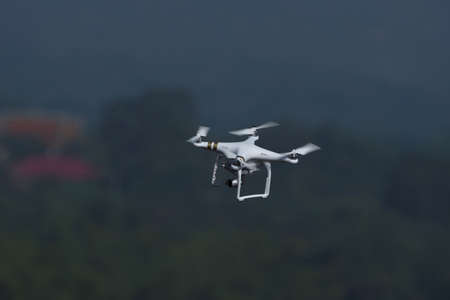 Drone quad copter with digital camera flying and hovering in landscape background.の写真素材