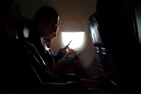 KRABI, THAILAND - 6 MAY 2018 : The passenger watching Mobile phone near window in morning on the airplane Thailand.のeditorial素材