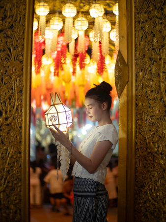 Beautiful Asian women holding a traditional paper lantern during Yi peng lantern festival at Wat Phra That Hariphunchai, Lamphun province, Thailand.の写真素材