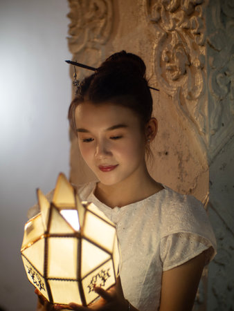 Beautiful Asian women holding a traditional paper lantern during Yi peng lantern festival at Wat Phra That Hariphunchai, Lamphun province, Thailand.の写真素材
