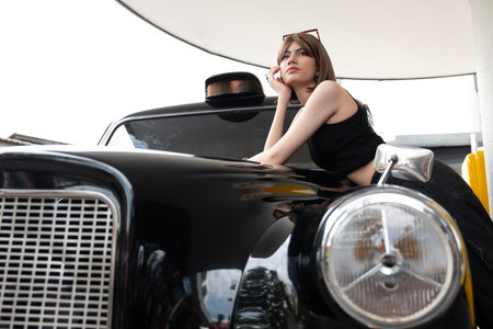 A beautiful young woman takes a photo with classic car.