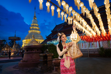 Beautiful Asian women holding a traditional paper lantern during Yi peng lantern festival at Wat Phra That Hariphunchai, Lamphun province, Thailand.の写真素材