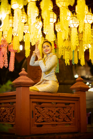 Beautiful Asian women holding a traditional paper lantern during Yi peng lantern festival at Wat Phra That Hariphunchai, Lamphun province, Thailand.の写真素材