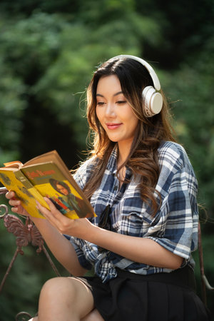A beautiful Asian teenage girl is happily listening to music with headphones.