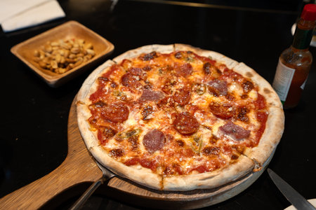 Pepperoni pizza and peanuts on a restaurant tableの写真素材