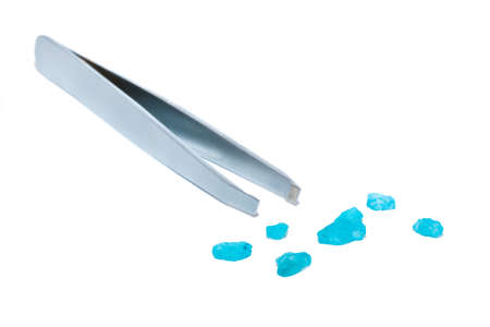 Tweezers and sprinkled blue bath salt sprinkled at white backgroundの写真素材