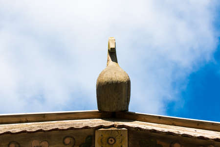 Wooden horse on the roof of traditional Russian cottage at the background of blue sky and cloudsの写真素材