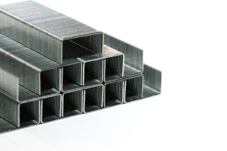 A pyramid of metal staples for stationery stapler at a white background close-up