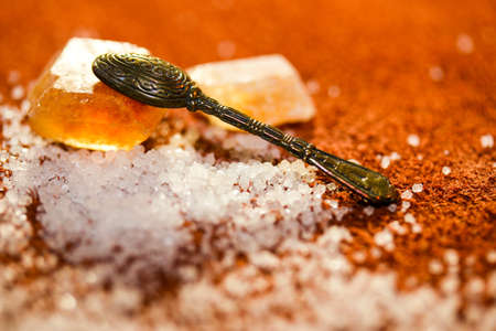 Tea spoon on the sweet crystal of sugar at a light brown backgroundの写真素材