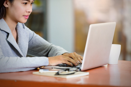 Beautiful businesswoman uses a laptop computer in the office. With the phone and notebook placed on...