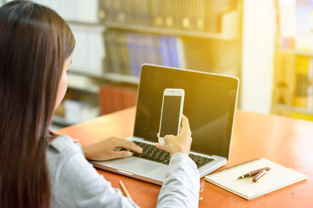 Beautiful businesswoman using mobile phone in office. With computer laptop  on the table as a background.
Business and Technology Concepts.の写真素材