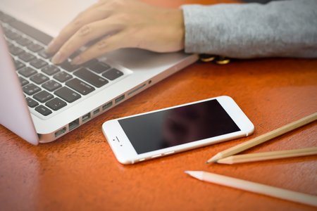 Mobile phone on wooden desk with a laptop computer. Business and Technology Concepts.の写真素材