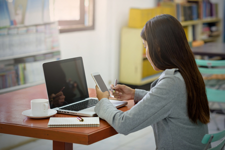 Beautiful Asian businesswoman using a mobile phone with a laptop in the office. Business, Financial and Technology Concepts.の写真素材