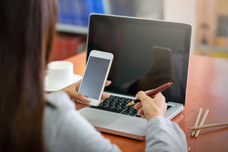 Beautiful Asian businesswoman using a mobile phone with a laptop in the office. Business, Financial and Technology Concepts.の写真素材