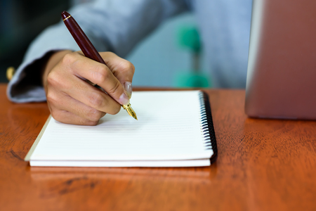 Beautiful Asian businesswoman is taking notes on her notebook while using the tablet in her office. Finance, Banking and Technology Concepts.の写真素材