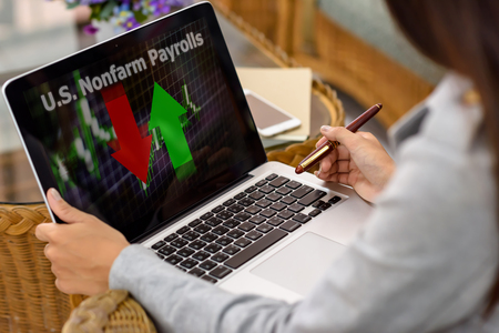 U.S. Nonfarm Payrolls word with businesswoman holding a pen looking at a laptop computer screen.の写真素材