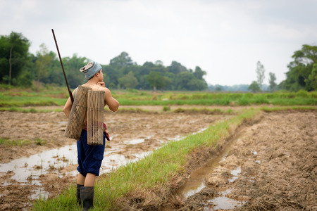 Male farmer carrying a rifle walks along.の写真素材