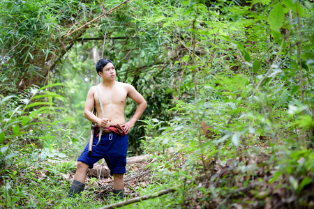 Asian man farmer carrying a rifle walks along in the forest background. Hunting and the way of life of rural people in Thailand concept.の写真素材