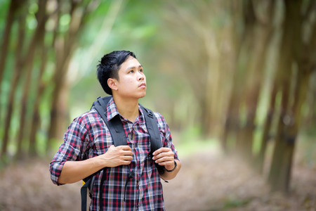Happy Asian man backpack in the rubber plantation background. Travel and holiday concept.の写真素材