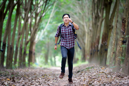 Happy Asian man backpack run in the rubber plantation background. Travel and holiday concept.の写真素材