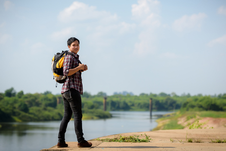 An Asian tourist man carrying a backpack enjoying a river. Holidays and nature concepts.の写真素材