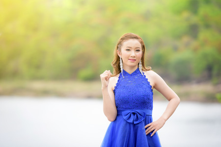 Beautiful woman wear blue evening dress over mountains and rivers background.の写真素材