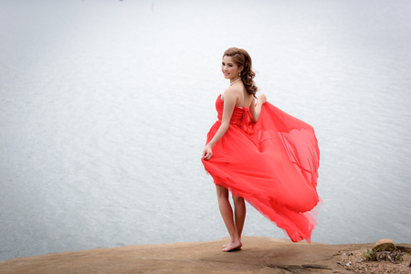 Beautiful woman wear red evening dress enjoying on the mountain.の写真素材