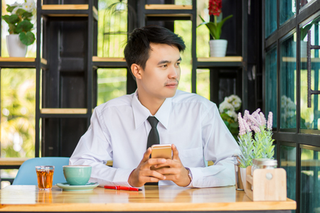 Business man using mobile phone while sitting in the coffee shop.の写真素材