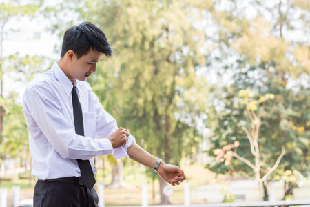 A young businessman is folding a white sleeve on his balcony.の写真素材