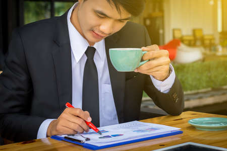 Businessman drinking coffee and reading a report in a coffee shop.の写真素材
