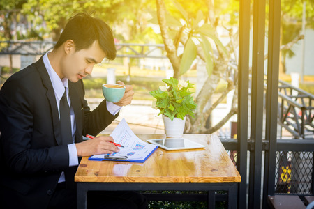 Businessman drinking coffee and reading a report in a coffee shop.の写真素材