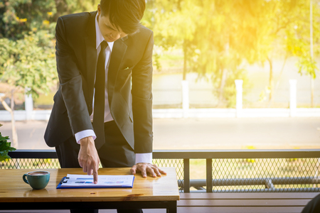 Finger of business man pointing to the paper report on the table in cafe.の写真素材