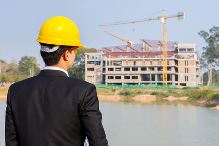 Businessman looking at building with crane.の写真素材