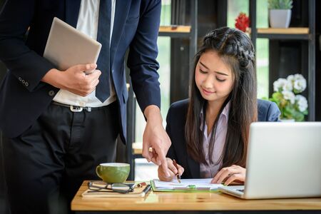 Business team with businessman pointing to a report paper and a business woman writing a report.