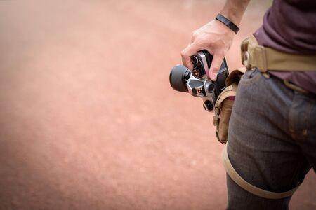 Photographer. Portrait of handsome stylish man holding retro camera on the road.の写真素材