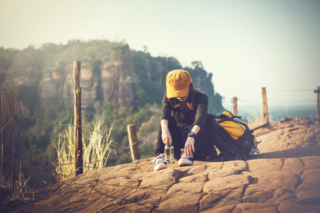 A tourist wearing a red hat is sitting tired on the mountain.の写真素材