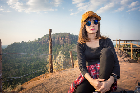 A tourist wearing a red hat is sitting tired on the mountain.の写真素材