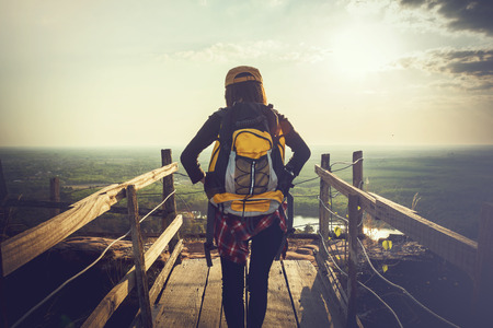 Tourist young woman wearing hat enjoying stand in wood bridge on the mountains.の写真素材