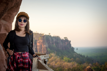 Tourist young woman wearing hat enjoying stand in wood bridge on the mountains.の写真素材