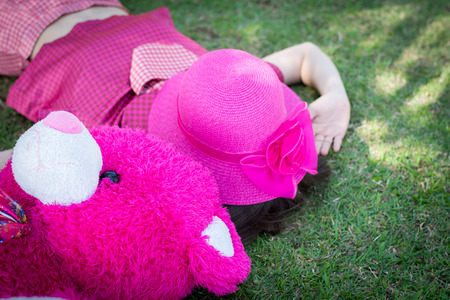 Happy woman sleep with doll on the grass near the river.の写真素材